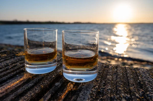 Drinking single malt Scotch whisky at sunset with sea, ocean or river view, private whisky distillery tours in Scotland, UK