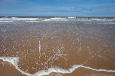 Kuzey deniz dalgaları ve kumlu plajlar güneşli bir günde ve mavi gökyüzünde