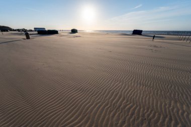 Küçük Belçika kasabası De Haan 'daki sarı kumlu sahil ya da Le Coq sur mer, lüks tatil beldesi, gün batımında yaz tatili