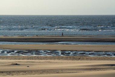 Küçük Belçika kasabası De Haan 'daki sarı kumlu sahil ya da Le Coq sur mer, lüks tatil beldesi, gün batımında yaz tatili