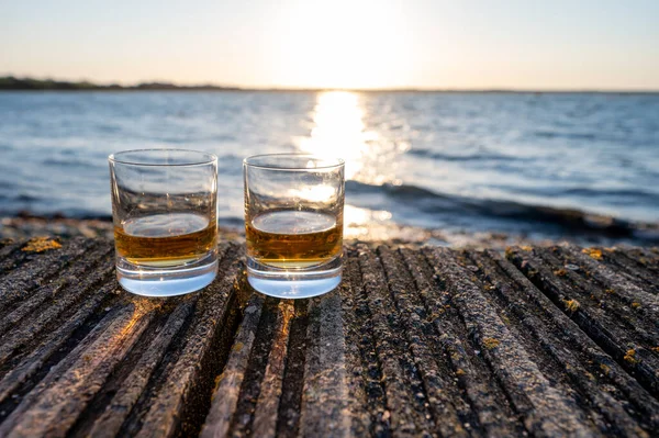 Drinking single malt Scotch whisky at sunset with sea, ocean or river view, private whisky distillery tours in Scotland, UK