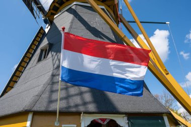 Hollanda bayrağı ve arka planda tahıl öğütmek için kullanılan eski geleneksel yel değirmeni