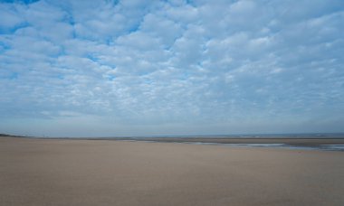 Küçük Belçika kasabası De Haan veya Le Coq sur mer 'deki sarı kumlu sahilde alçak uçuş süresi, lüks tatil beldesi, güneşli bir günde yaz tatili