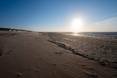 Küçük Belçika kasabası De Haan 'daki sarı kumlu sahil ya da Le Coq sur mer, lüks tatil beldesi, gün batımında yaz tatili