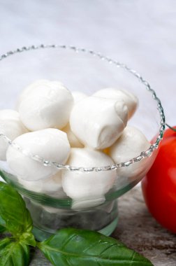 Kırmızı domates ve taze yeşil fesleğenle servis edilen taze, yumuşak mozzarella topları.