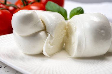 Güney İtalyan yumuşak beyaz mozzarella peyniri bufalo ineklerinden yapılmış taze domates ve taze yeşil fesleğenle servis edilen süt yakın mesafede.