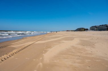 Küçük Belçika kasabası De Haan 'daki sarı kumlu sahil ya da Le Coq sur mer, lüks tatil beldesi, güneşli bir günde yaz tatili