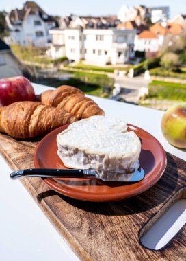 Normandiya 'dan taze kruvasan ve peynirli Fransız kahvaltısı. Kalp şeklinde neufchatel, Fransız köyü manzaralı açık havada servis ediliyor.