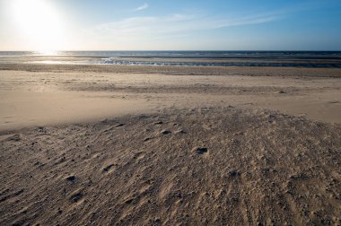 Küçük Belçika kasabası De Haan 'daki sarı kumlu sahil ya da Le Coq sur mer, lüks tatil beldesi, gün batımında yaz tatili