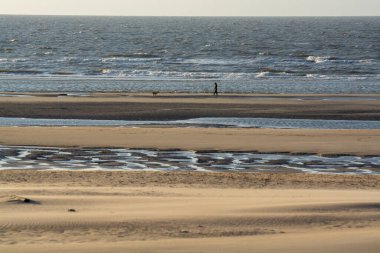 Küçük Belçika kasabası De Haan 'daki sarı kumlu sahil ya da Le Coq sur mer, lüks tatil beldesi, gün batımında yaz tatili