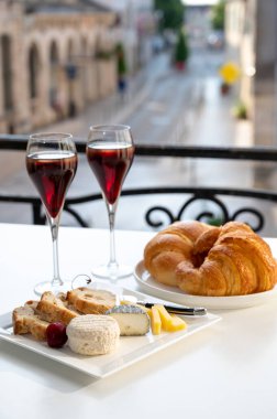 Kir Royal içen, Fransız aperatifi. Krema ve şampanyayla kaplanmış, genellikle flüt bardaklarıyla servis edilen, eski Fransız köyü manzaralı.