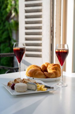 Kir Royal içen, Fransız aperatifi. Krema ve şampanyayla kaplanmış, genellikle flüt bardaklarıyla servis edilen, eski Fransız köyü manzaralı.
