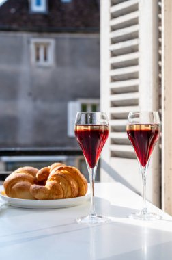 Kir Royal içen, Fransız aperatifi. Krema ve şampanyayla kaplanmış, genellikle flüt bardaklarıyla servis edilen, eski Fransız köyü manzaralı.
