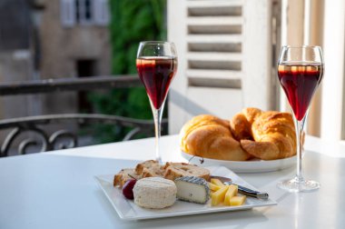 Kir Royal içen, Fransız aperatifi. Krema ve şampanyayla kaplanmış, genellikle flüt bardaklarıyla servis edilen, eski Fransız köyü manzaralı.