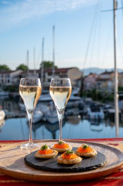 Rus tarzı parti, iki bardak soğuk şampanya, kırmızı havyarlı bulanık ve Saint-Tropez yakınlarındaki Port Grimaud manzaralı, yazın Fransız Riviera 'sında tatiller.