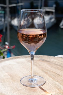 Fransız Riviera Cote d 'Azur' da yaz mevsimi, Cotes de Provence 'den soğuk gül şarabı içmek Port Grimaud, Var, Fransa' da güneşli açık teraslarda arka planda botlar ve yatlarla