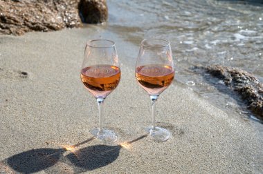 Provence 'de yaz mevsimi, güneşli bir günde Saint-Tropez yakınlarındaki kumlu sahilde iki bardak soğuk gül şarabı, Var Bölümü, Fransa