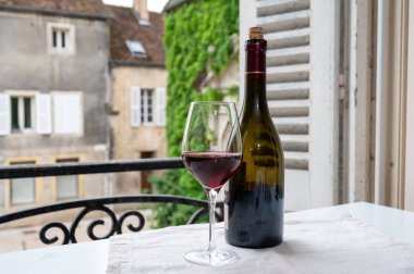 Burgundy şarap bölgesindeki Grand Cru Pinot üzüm bağlarından şarap, cam ve bir şişe kırmızı şarap ve eski kasaba caddesinin görüntüsü Fransa 'nın Burgundy şarap bölgesinde