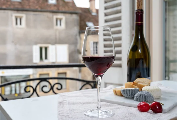 Tasting of burgundy red wine from grand cru pinot noir  vineyards with french goat cheeses and view on old town street in Burgundy Cote de Nuit wine region, France