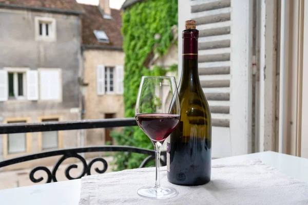 Burgundy şarap bölgesindeki Grand Cru Pinot üzüm bağlarından şarap, cam ve bir şişe kırmızı şarap ve eski kasaba caddesinin görüntüsü Fransa 'nın Burgundy şarap bölgesinde