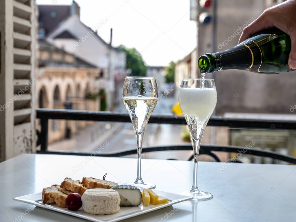 Romantic party with two glasses of white cold champagne sparkling wine with bubbles and view on old street in French village
