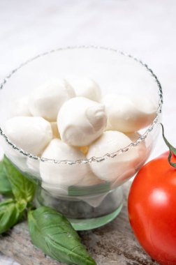 Kırmızı domates ve taze yeşil fesleğenle servis edilen taze, yumuşak mozzarella topları.