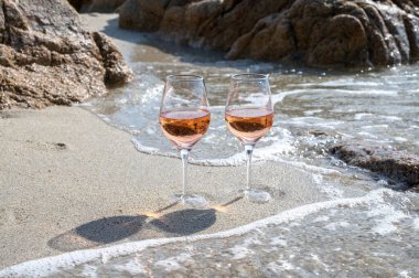 Provence 'de yaz mevsimi, güneşli bir günde Saint-Tropez yakınlarındaki kumlu sahilde iki bardak soğuk gül şarabı, Var Bölümü, Fransa