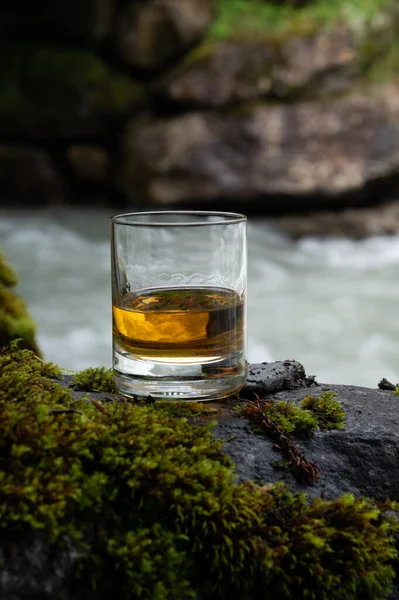 スコットランドを背景に流れるような渓流を背景にした強いスコッチシングルモルトウイスキーのグラス — ストック写真