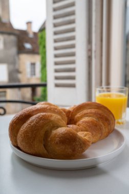 Fransız kahvaltısı, taze kruvasan tereyağlı pasta arkaplanda lezzetli portakal suyu ve eski Fransız evleriyle servis ediliyor.