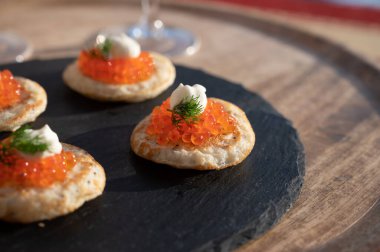 Akşam yemeği için lezzetli aperatif, küçük gözlemeler açık havada servis edilen kırmızı balık havyarıyla bulanık.