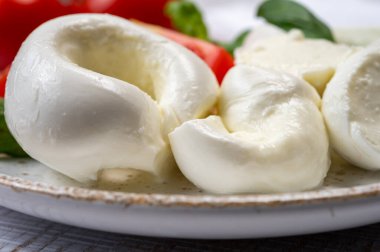 Güney İtalyan yumuşak beyaz mozzarella peyniri bufalo ineklerinden yapılmış taze domates ve taze yeşil fesleğenle servis edilen süt yakın mesafede.