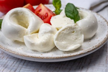 Güney İtalyan yumuşak beyaz mozzarella peyniri bufalo ineklerinden yapılmış taze domates ve taze yeşil fesleğenle servis edilen süt yakın mesafede.