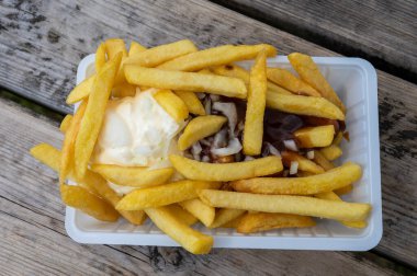 Köri ve mayonez soslu patates cipsi ve ahşap masada soğan.