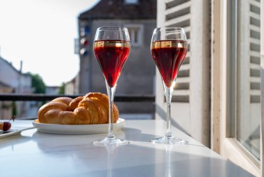 Kir Royal içen, Fransız aperatifi. Krema ve şampanyayla kaplanmış, genellikle flüt bardaklarıyla servis edilen, eski Fransız köyü manzaralı.
