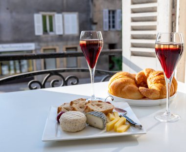 Kir Royal içen, Fransız aperatifi. Krema ve şampanyayla kaplanmış, genellikle flüt bardaklarıyla servis edilen, eski Fransız köyü manzaralı.