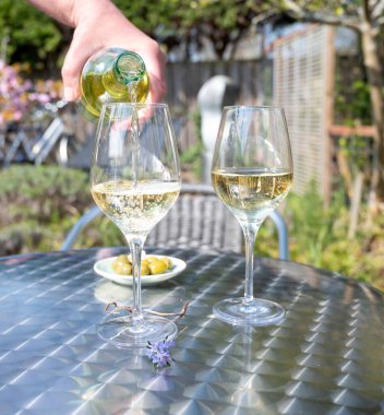 Güneşli bir günde bahar bahçesinde açık terasta beyaz şarap içmek.