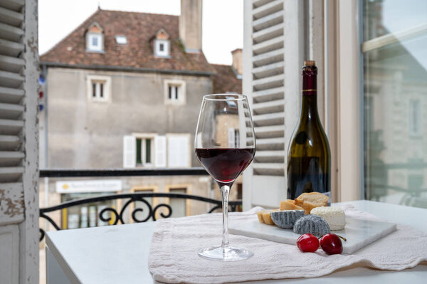 Дегустация бордового красного вина из виноградников Grand Cru pinot noir с французскими козьими сырами и видом на старую улицу города в винодельческом регионе Бургундия-Кот-де-Нуит, Франция