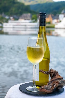 Mosel şarap bölgesinde beyaz kaliteli riesling şarabı tatmak için Mosel nehri ve Almanya 'nın güneşli günlerinde arka planda kalan eski Alman kasabası ile birlikte açık havada servis edilir.