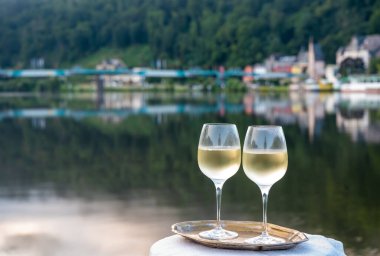 Mosel şarap bölgesinde beyaz kaliteli riesling şarabı tatmak için Mosel nehri ve Almanya 'nın güneşli günlerinde arka planda kalan eski Alman kasabası ile birlikte açık havada servis edilir.