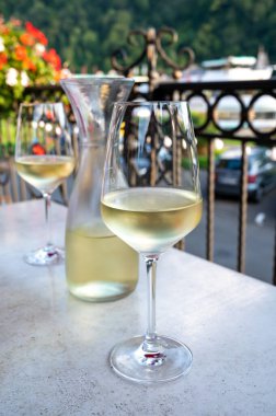 Beyaz kaliteli şarap tatma Mosel şarap bölgesinde açık terasta servis edilir ve güneşli bir günde arka planda eski Alman kasabası, Almanya