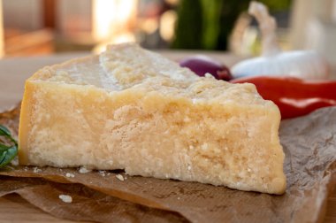 Peynir koleksiyonu, olgun inek peyniri pasmesan parmegiano reggiano ve arka planda İtalyan evleri güneşli bir günde