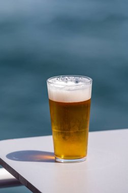 Güneşli bir yaz gününde, terasta deniz manzaralı soğuk bira servis edilir.