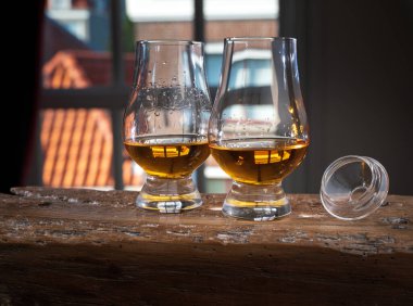 Tek malt viski bardağında servis edilen viski bardağı, eski pencere manzaralı ve ahşap kirişli evler.