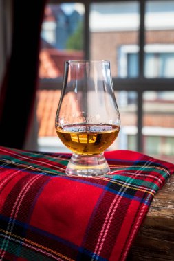 Tek malt viski bardağında servis edilen viski bardağı eski pencere manzaralı ve ahşap kirişli evler ve kırmızı tartan.