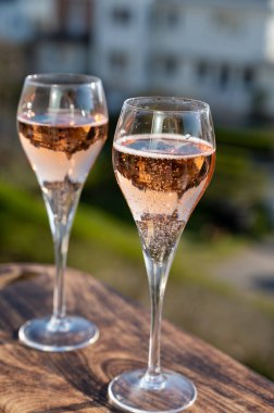 Gül şampanyası içmek flüt bardaklarından köpüklü şarap Fransa 'nın açık terasında güneşli bir günde