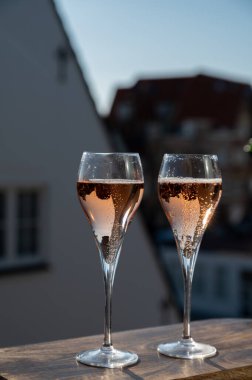 Gül şampanyası içmek flüt bardaklarından köpüklü şarap Fransa 'nın açık terasında güneşli bir günde