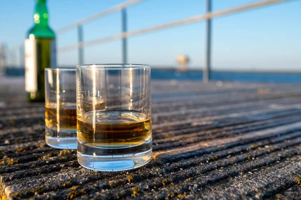 海または川の景色を望む日没時にシングルモルトスコッチウイスキーを飲む スコットランド 英国のプライベートウイスキー蒸留所ツアー — ストック写真