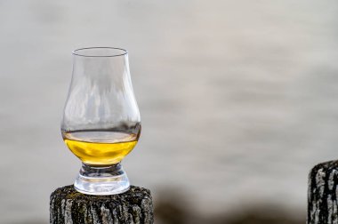 İskoçya 'da deniz kıyısında viski tatmak, viski kadehli eski tahta direkler.
