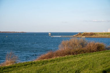 Scharendijke 'de yürürken, Hollanda' nın Zealand şehrinde eski evleri ve Grevelingenmeer 'in mavi sularıyla küçük bir kasaba manzarası var.