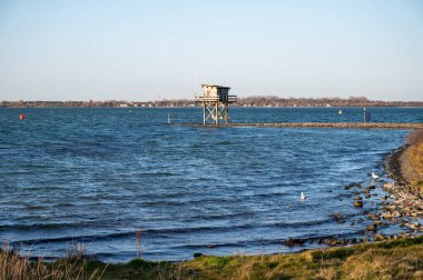 Scharendijke 'de yürürken, Hollanda' nın Zealand şehrinde eski evleri ve Grevelingenmeer 'in mavi sularıyla küçük bir kasaba manzarası var.